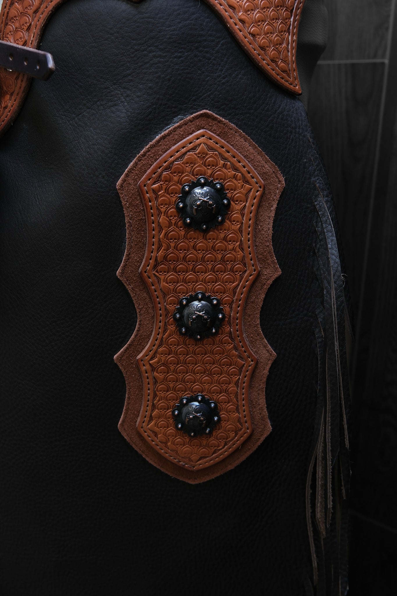 Close up of decorative leather and conchos on a set of chinks