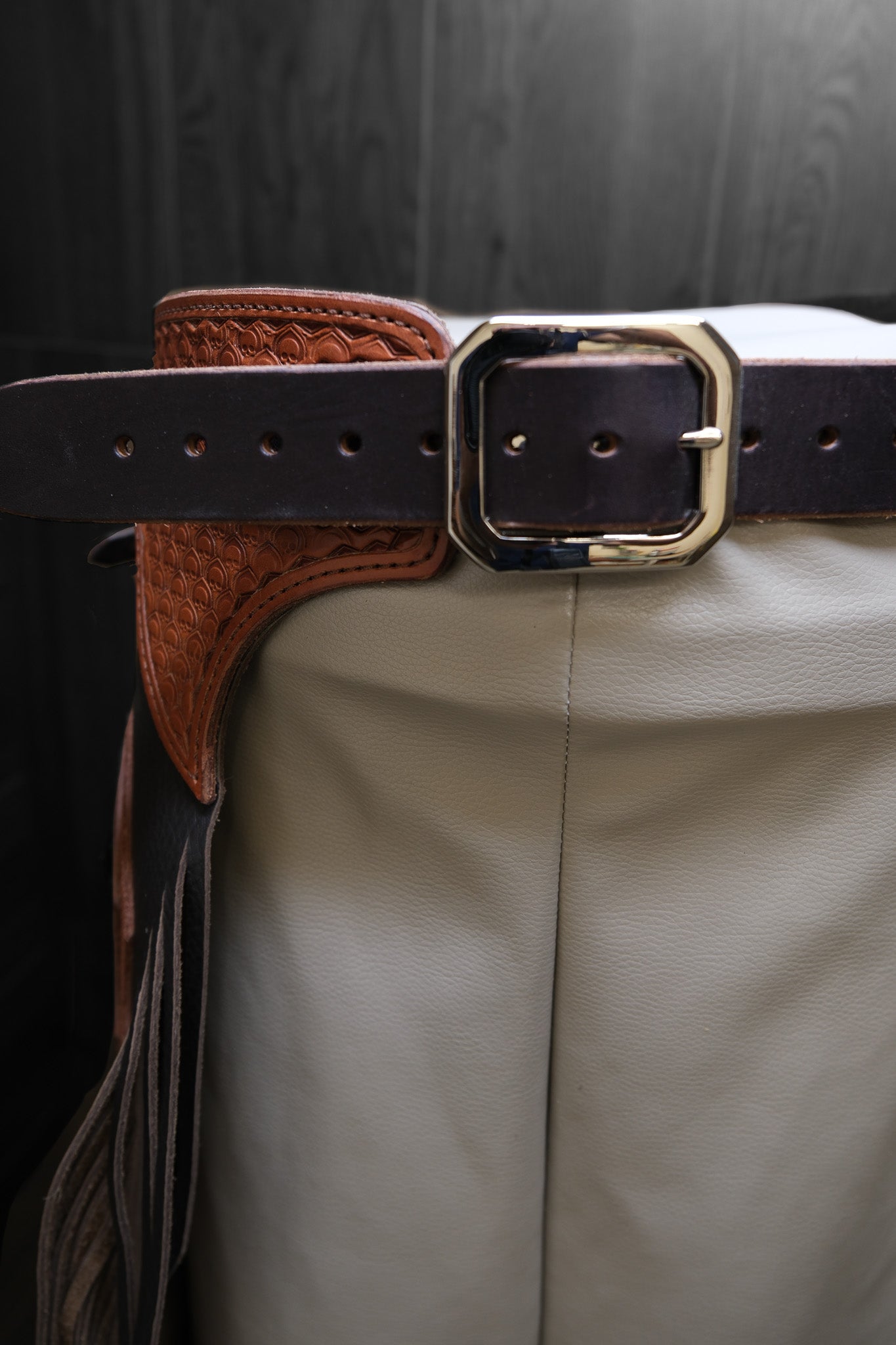 Close-up of a brown leather chinks belt with a gold buckle.